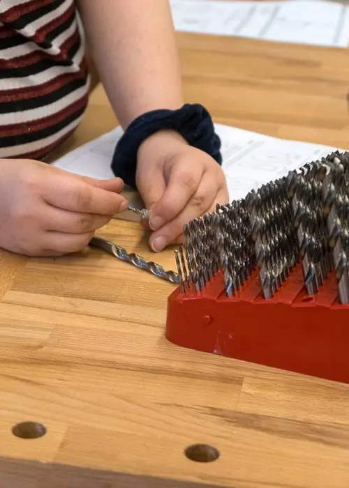 DEICHMANN-Stiftung | Chancengleichheit in der Berufsorientierung – Berufsorientierungswerkstatt an der Gesamtschule Nord in Essen  Chancengleichheit in der Berufsorientierung – Das Bild zeigt einen Schüler in der Metallwerkstatt der Gesamtschule Nord in Essen bei der Auswahl von Bohraufsätzen.