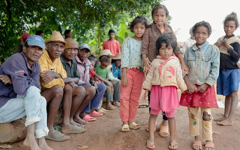 Madagascar Mobile Clinic – Kinder stehen und Erwachsene sitzen unter einem Baum in Madagaskar