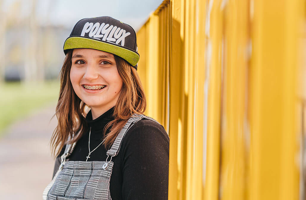 deichmann-stiftung-projekt-Bildung-Wissenschaft-Forschung-Trumpf lächelnde junge Frau mit Käppi und Zahnspange