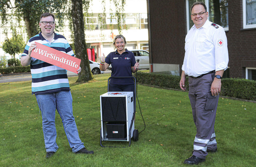deichmann-stiftung-projekt-not-katastrophenhilfe-Deutsches-rotes-kreuz Drei Personen mit Rot-Kreuz-Uniform präsentieren einen Bautrockner