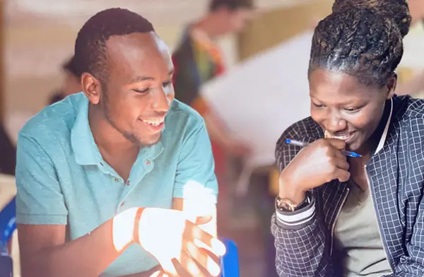 Deichmann Stiftung | Sozialunternehmen Uganda – Mentorenprogramm Sozialunternehmen Uganda – zwei Personen diskutieren fröhlich – sie sehen motoviert aus – eine Person erklärt der anderen etwas – Mentorenprogramm