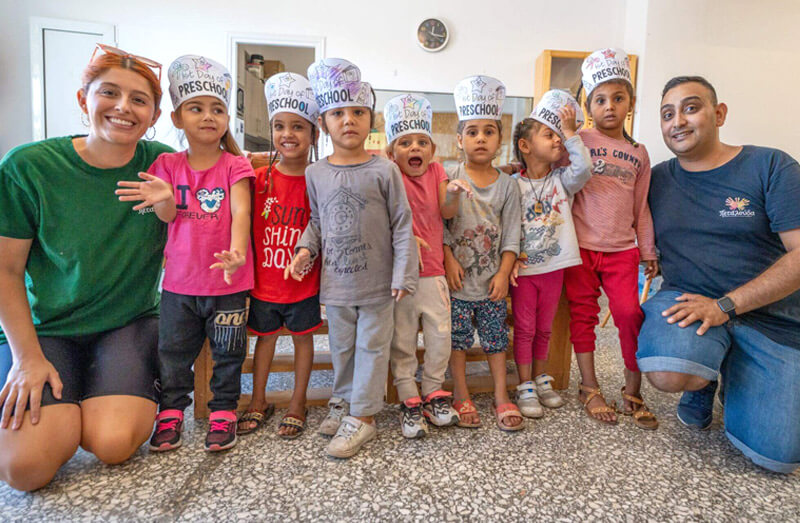 Deichmann Stiftung | Roma-Integration Griechenland – frühkindliche Bildung – Vorschulkinder mit gebastelten Hüten mit Preschool-Beschriftung